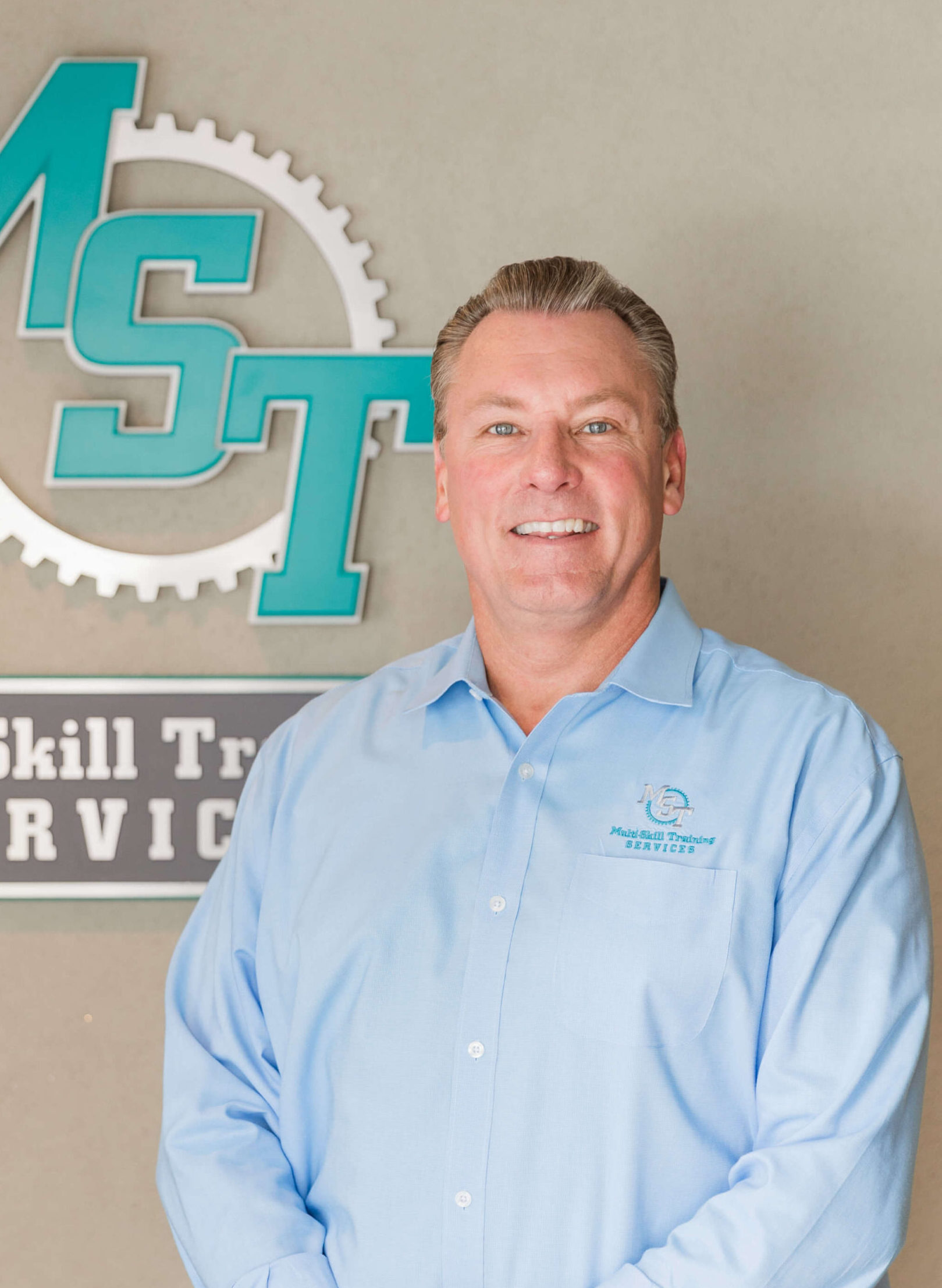 Tony Ericson (VP, Operator Excellence) standing next to MST sign on a wall